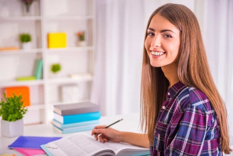 Service Featured Image - teenager smiling with orthodontic appliance while doing homework